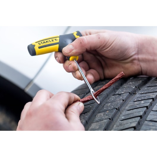 Stanley STHT80891-0 tire repair tool kit used to plug a puncture in a car tire, close-up.