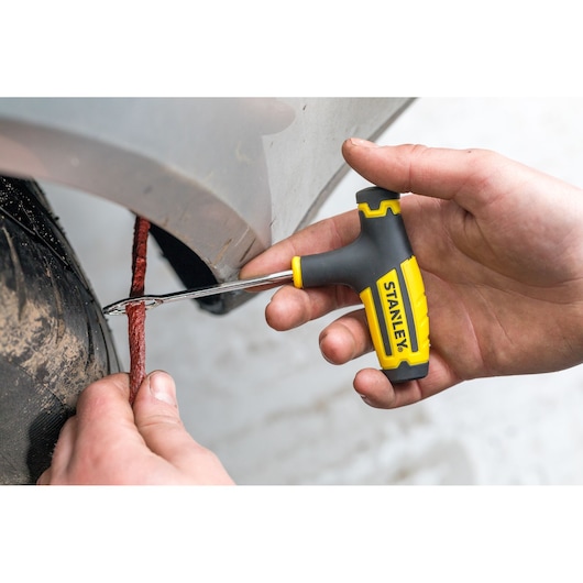 Stanley STHT80891-0 tire repair tool with yellow and black handle used to fix a punctured tire in close-up.
