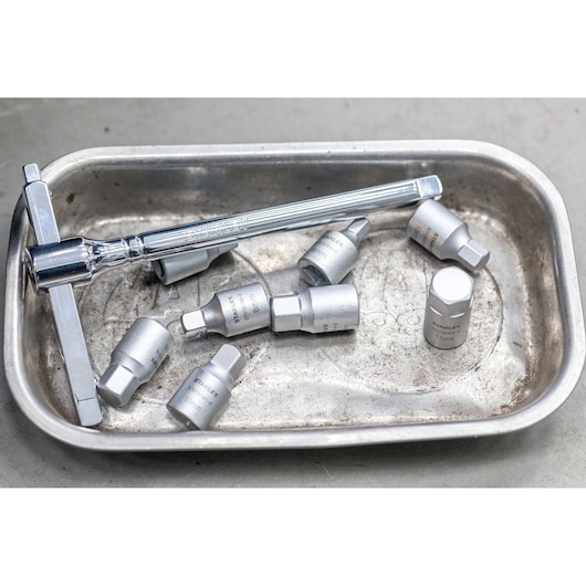 STANLEY STHT81579-0 socket wrench and hex sockets in metal tray, close-up view.