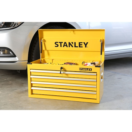 STANLEY STMT1-75062 yellow metal tool chest with open lid, four drawers, shown in a garage next to a car.
