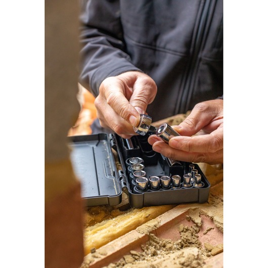STANLEY STMT82672-0 socket set in black case, hands selecting a socket, close-up on worksite.