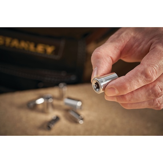 Photo of STANLEY STMT86106-0 socket held in hand with other sockets in background, tool photography.