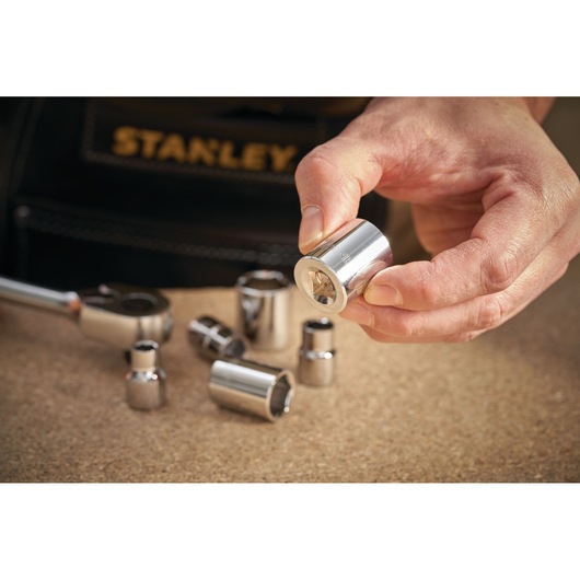 STANLEY STMT86303-0 socket set pieces held and arranged on a workbench, close-up photography.