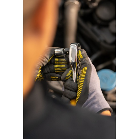 STANLEY STMT86511-0 ratchet handle held by gloved hands during automotive work, close-up photography.