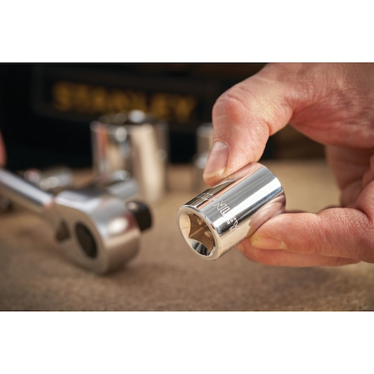 STANLEY STMT86519-0 socket being held by hand with ratchet and other sockets in background, close-up photo.