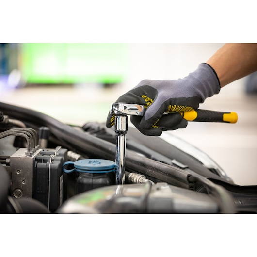 Photo of STANLEY STMT88942-0 ratchet wrench used for automotive repair, gloved hand holding tool over engine.