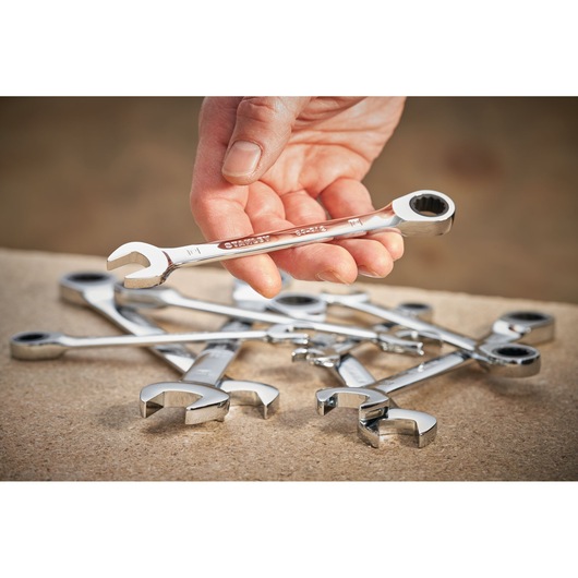 Photo of STANLEY STMT89916-0 ratcheting wrench held in hand with other wrenches on a work surface.
