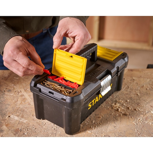 STANLEY STST1-75515 toolbox with open yellow compartment, screws and red anchors, photo on workbench.