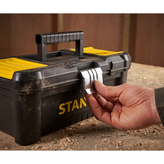 Photo of STANLEY STST1-75515 toolbox with yellow lid and metal latch being opened on workbench.