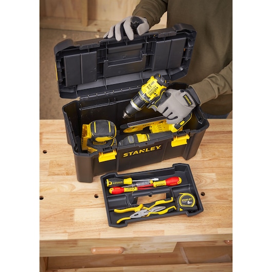 STANLEY STST1-75520 toolbox with various hand tools and a drill, photo from above on workbench.