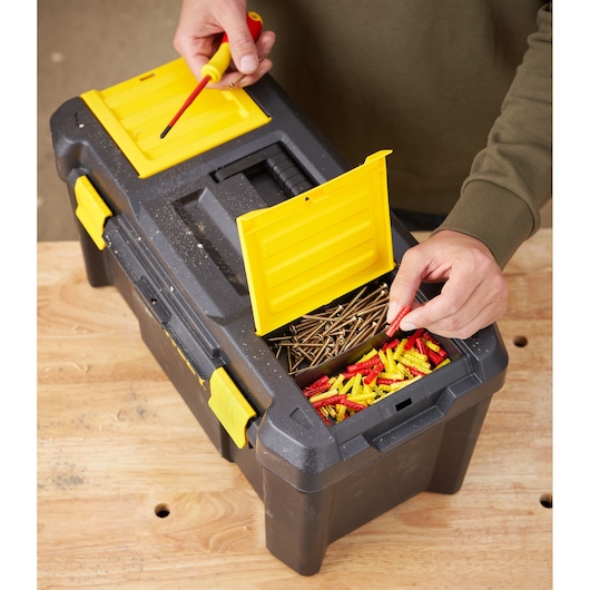 STANLEY STST1-75520 black and yellow toolbox on table, open top compartments with screws and wall plugs, top view.