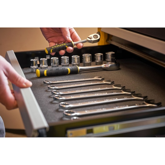 STANLEY STST74306-1 photography of hand holding ratchet in drawer with wrenches and sockets.