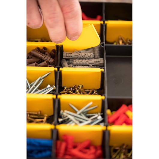 STANLEY STST81680-1 photography of hand opening yellow bin with assorted screws and wall plugs.