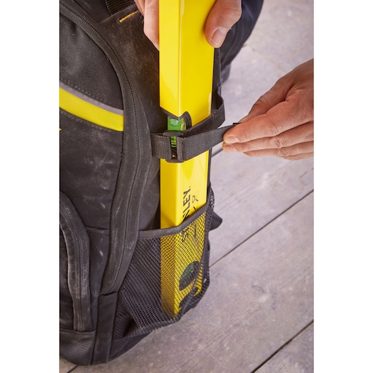 STANLEY STST83307-1 photography of black backpack with mesh pocket holding yellow level tool, close-up view.