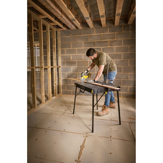 STANLEY STST83492-1 folding work table in use during construction, black tabletop, sturdy legs.