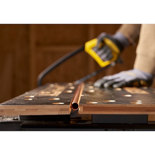 STANLEY STST83800-1 photography of workbench holding copper pipe while being cut with saw.