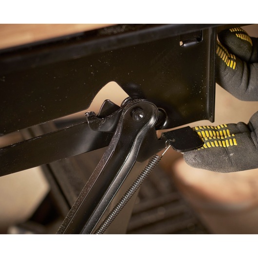 STANLEY STST83800-1 photography of black metal hinge with spring being adjusted by gloved hand.