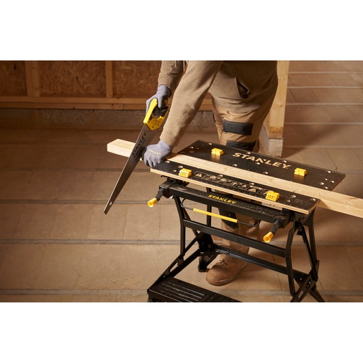 Photo of STANLEY STST83800-1 workbench used for woodworking, black tabletop with yellow clamps, workshop setting.