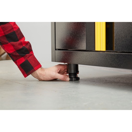 STANLEY STST97595-1 cabinet adjustable leg close-up on concrete floor, hand turning knob.
