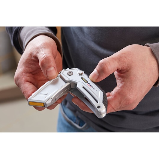 Photo of STANLEY XTHT0-10502 utility knife held in hand, silver folding design with visible logo.