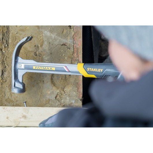 STANLEY XTHT1-51148 claw hammer with FATMAX branding, closeup in use on wood and concrete.